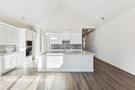 Kitchen with hardwood / wood-style floors, stainless steel microwave, white cabinetry, and tasteful backsplash