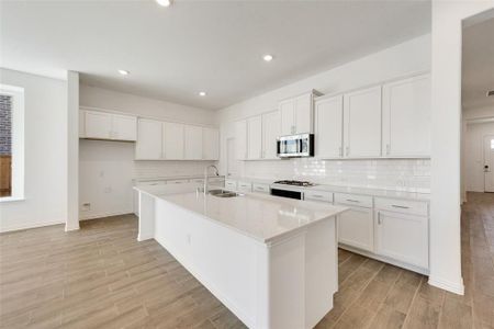 Kitchen featuring light hardwood / wood-style flooring, white cabinetry, a kitchen island with sink, and sink