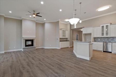 Kitchen with stainless steel dishwasher, a multi sided fireplace, ceiling fan, and wood-type flooring