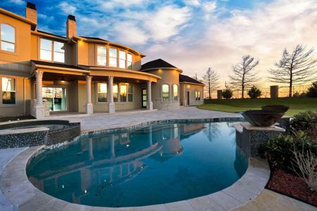 Pool at dusk with an in ground hot tub, a lawn, and a patio area