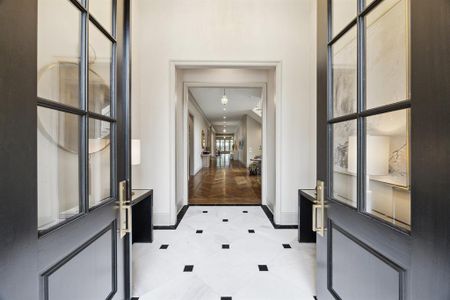 Welcome inside! Bold black double doors open to a luxurious foyer, where striking marble floors with black accents meet warm herringbone hardwood. This elegant entryway, with its designer touches, creates an unforgettable first impression.