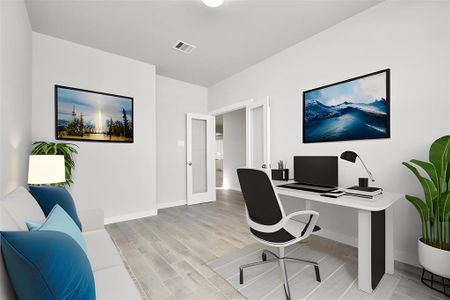 At the forefront, a refined home office beckons productivity and focus. Luxurious details like wood look tile, custom paint, expansive windows with privacy blinds, and French doors create an inspiring workspace. Sample photo of completed home with similar floor plan. As-built interior colors and selections may vary.