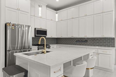 The kitchen features elegant white cabinets, a spacious kitchen island, and stylish gold fixtures, creating a modern and luxurious culinary space.