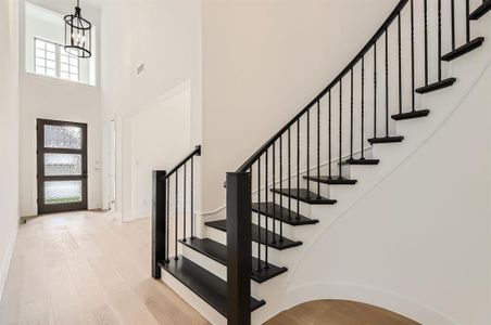 Foyer with a towering ceiling, light hardwood / wood-style floors, and a chandelier