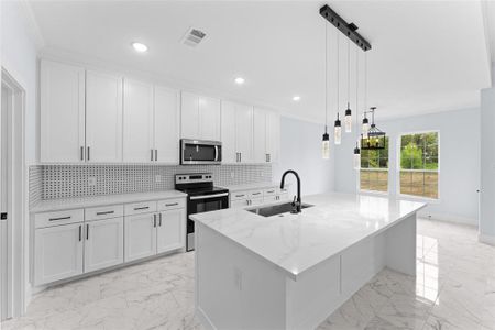 Kitchen with a kitchen island with sink, white cabinetry, stainless steel appliances, sink, and light stone countertops