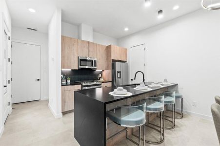 Stainless steel appliances, quartz countertops, and modern flat edge cabinetry throughout the kitchen.