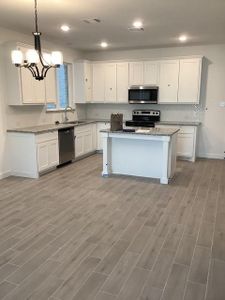 Kitchen featuring light stone counters, white cabinets, stainless steel appliances, and a kitchen island