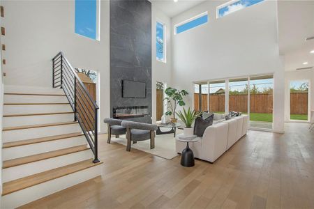 Living room featuring a high end fireplace, light hardwood / wood-style floors, and a towering ceiling