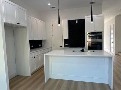 Kitchen featuring pendant lighting, light hardwood / wood-style floors, white cabinets, and stainless steel double oven