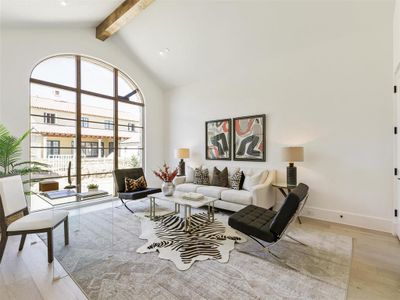 Living room with beam ceiling, light hardwood / wood-style flooring, and high vaulted ceiling