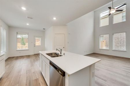 Kitchen with dishwasher, a kitchen island with sink, sink, white cabinetry, and ceiling fan