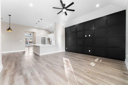 Unfurnished living room with a high ceiling, ceiling fan, and light wood-type flooring