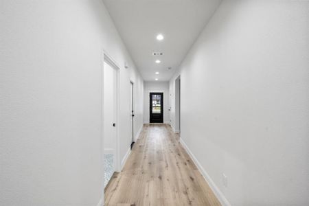 Hall featuring light wood-type flooring, baseboards, visible vents, and recessed lighting