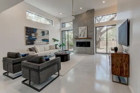 Living area with recessed lighting, a high ceiling, baseboards, a tiled fireplace, and finished concrete floors