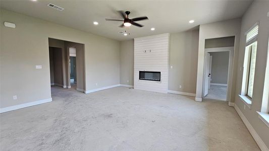 Unfurnished living room featuring ceiling fan and a large fireplace