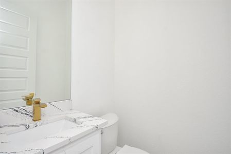 Elegant and modern, this powder room features a sleek quartz vanity with bold veining, complemented by luxurious gold fixtures. Bright and airy, its timeless design exudes sophistication and style.