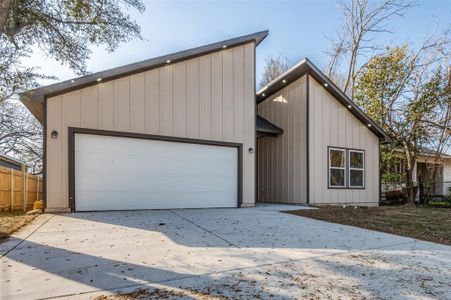 View of front of home with a garage, concrete driveway, and fence