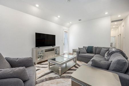 This modern living room features a spacious, light-filled living area. The open space and recessed lighting create a cozy, inviting atmosphere.