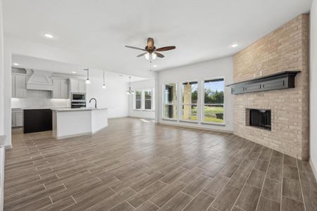 Unfurnished living room with ceiling fan with notable chandelier, sink, dark wood-type flooring, and a brick fireplace