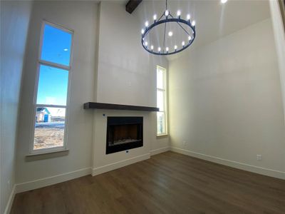 Unfurnished office/den with dark hardwood / wood-style flooring, plenty of natural light, a towering ceiling, and a chandelier