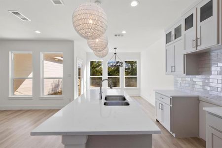 Kitchen featuring plenty of natural light, an island with sink, a chandelier, and sink