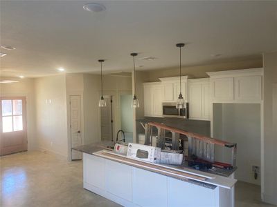 Kitchen with dark stone countertops, hanging light fixtures, and white cabinets