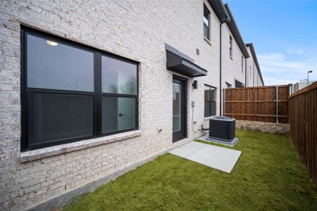 Back of house with brick siding, central AC unit, a lawn, and fence