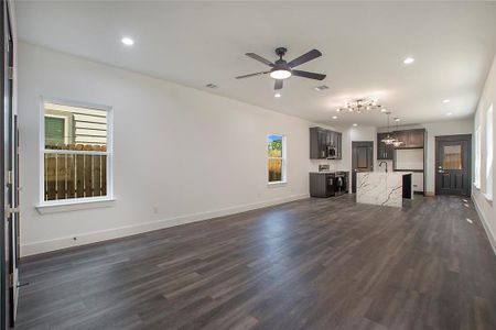 Unfurnished living room with dark hardwood / wood-style flooring, sink, and ceiling fan