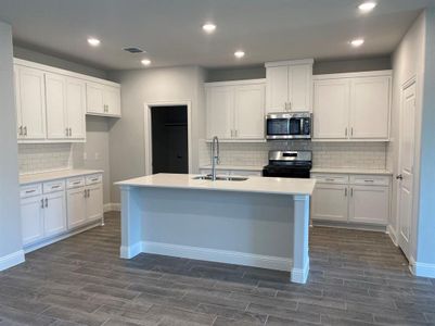 Kitchen with tasteful backsplash, sink, white cabinets, and stainless steel appliances