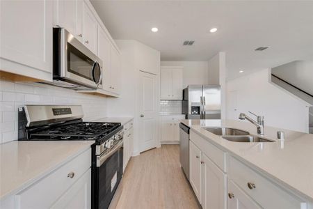 Kitchen featuring light hardwood / wood-style floors, white cabinetry, tasteful backsplash, stainless steel appliances, and sink