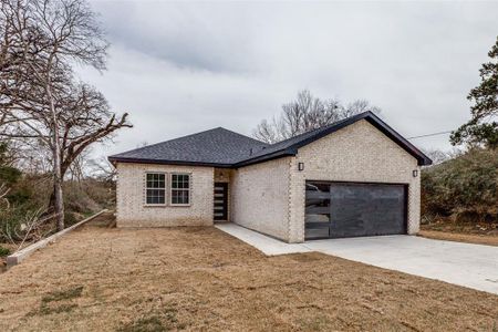 View of front of home with brick siding, a garage, driveway, and roof with shingles