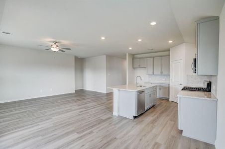 Kitchen includes an island with sink, tasteful backsplash, appliances with stainless steel finishes, and light hardwood / wood-style flooring