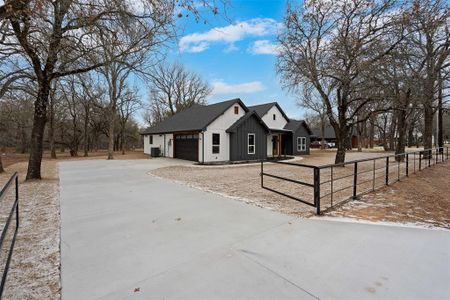 View of front of home with driveway, board and batten siding, an attached garage, and a fenced front yard