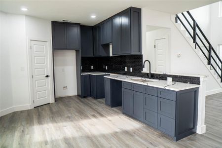 Kitchen featuring sink, decorative backsplash, light hardwood / wood-style flooring, and light stone countertops