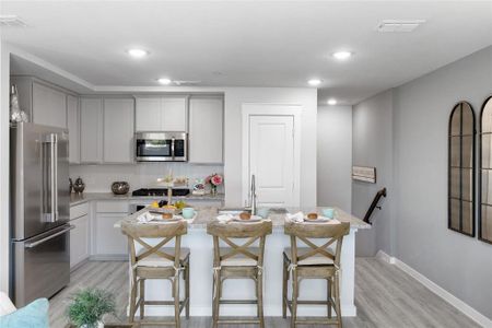 Kitchen featuring appliances with stainless steel finishes, a kitchen island, light hardwood / wood-style floors, and a breakfast bar