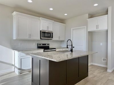 Kitchen with white cabinets, appliances with stainless steel finishes, and an island with sink