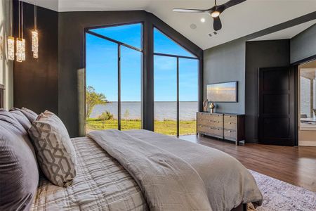 Bedroom featuring hardwood / wood-style floors, ceiling fan, a water view, and lofted ceiling