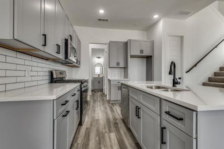 Kitchen with stainless steel appliances, sink, backsplash, light hardwood / wood-style flooring, and gray cabinetry