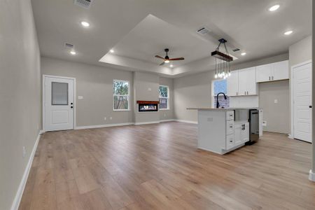 Kitchen featuring light wood-type flooring, white cabinetry, a kitchen island with sink, and ceiling fan