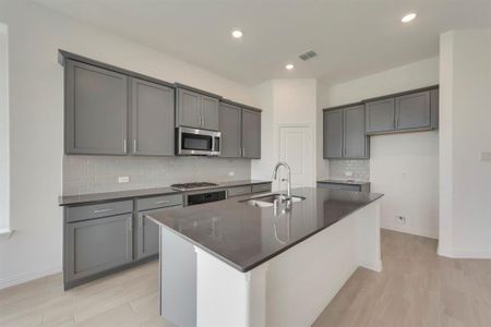 Kitchen with stainless steel appliances, sink, an island with sink, and backsplash