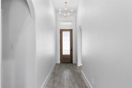 Entryway featuring an inviting chandelier, a towering ceiling, and light hardwood / wood-style flooring