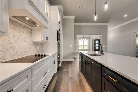 Kitchen featuring crown molding, backsplash, sink, black electric cooktop, and hardwood / wood-style flooring