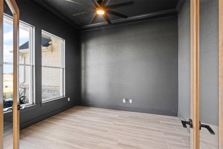 Empty room with crown molding, plenty of natural light, french doors, and light wood-type flooring