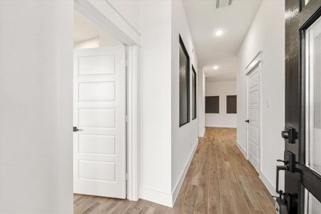 As you enter, you'll be greeted by wood-look tile flooring and 10 foot ceilings. The foyer features black accents throughout the hallway, adding a touch of modern elegance to the space.  To the left is bedroom #1 and the garage is located to the right. Straight ahead, you'll find the open-concept space that includes the dining, living, and kitchen areas.