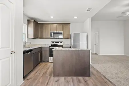 Kitchen featuring appliances with stainless steel finishes, light hardwood / wood-style floors, a center island, sink, and ceiling fan