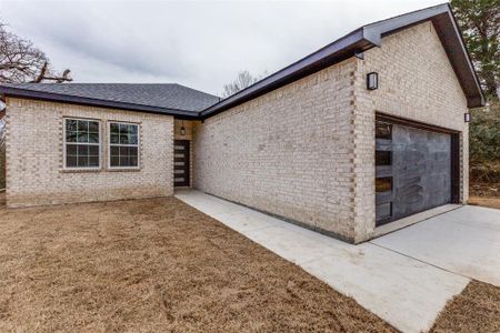 View of front facade with concrete driveway, brick siding, a garage, and roof with shingles