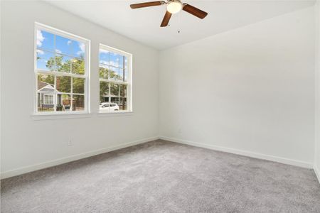 Carpeted empty room with plenty of natural light and ceiling fan