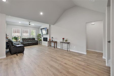 Living room featuring light wood-type flooring, ceiling fan, and vaulted ceiling