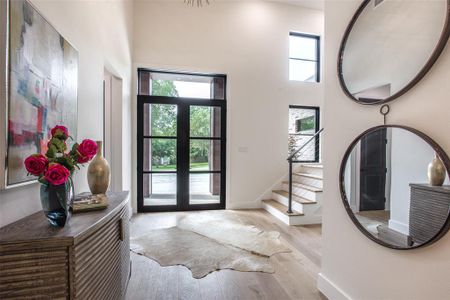 Foyer featuring french doors, light wood-type flooring, and a high ceiling