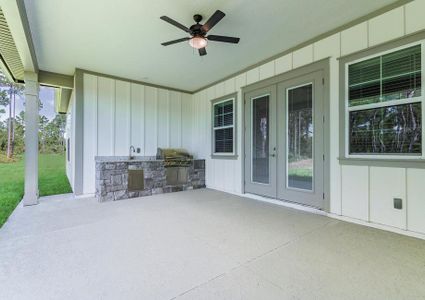 Covered outdoor kitchen with a built-in grill, sink and ceiling fan.